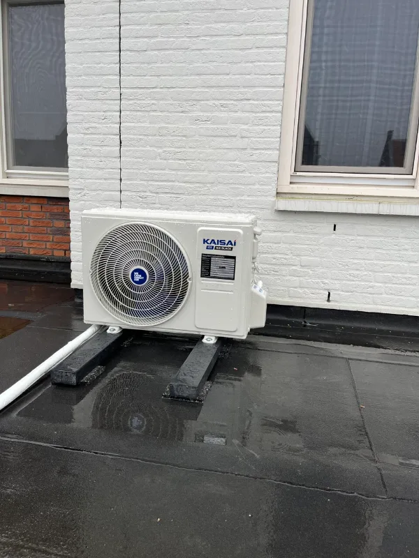Buitenunit van een airco tegen de gevel van een woning