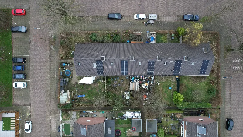 Rij woningen van bovenaf met per woning een passende paneelopstelling